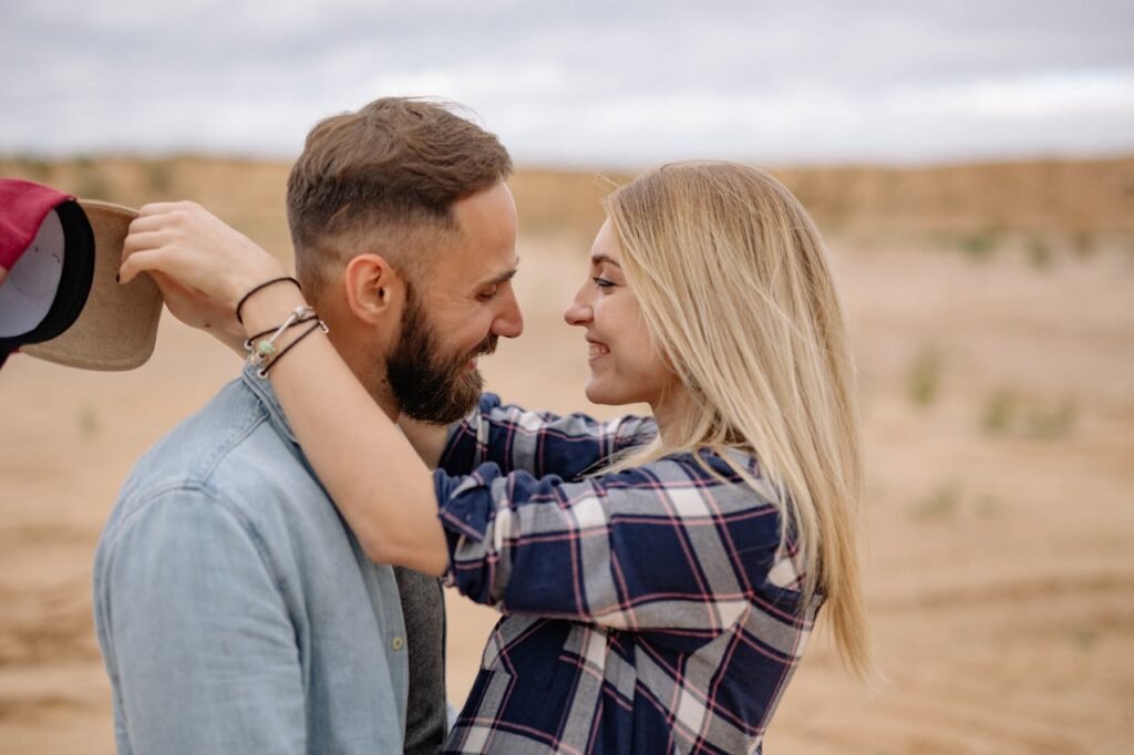 Relacionamento Interpessoal. Casal sorrindo um para o outro ao ar livre, demonstrando carinho e conexão emocional.