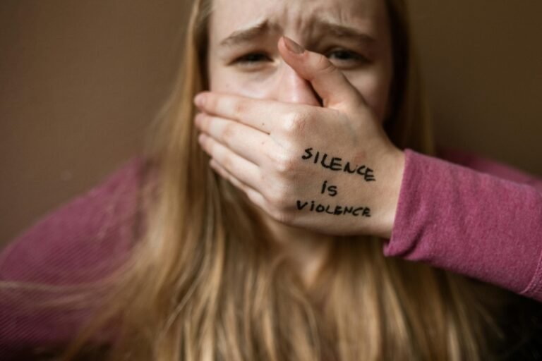 "Mulher com expressão de dor cobrindo a boca com a mão, onde está escrito 'Help', simbolizando sofrimento em um relacionamento tóxico."