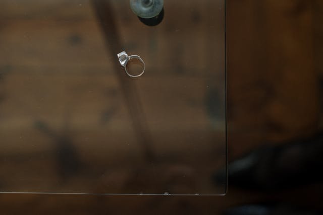 Aliança de casamento deixada sobre uma mesa de vidro, simbolizando a solidão a dois ou fim de um relacionamento.